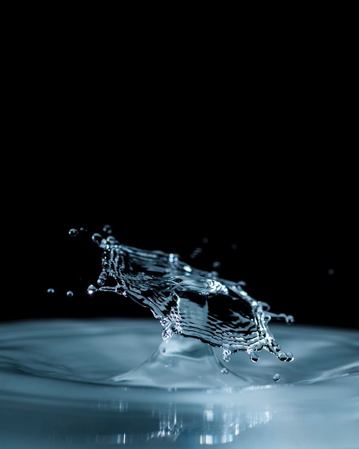 Captivating close-up of water splash captured with precision against a black backdrop, showcasing motion and fluid dynamics.